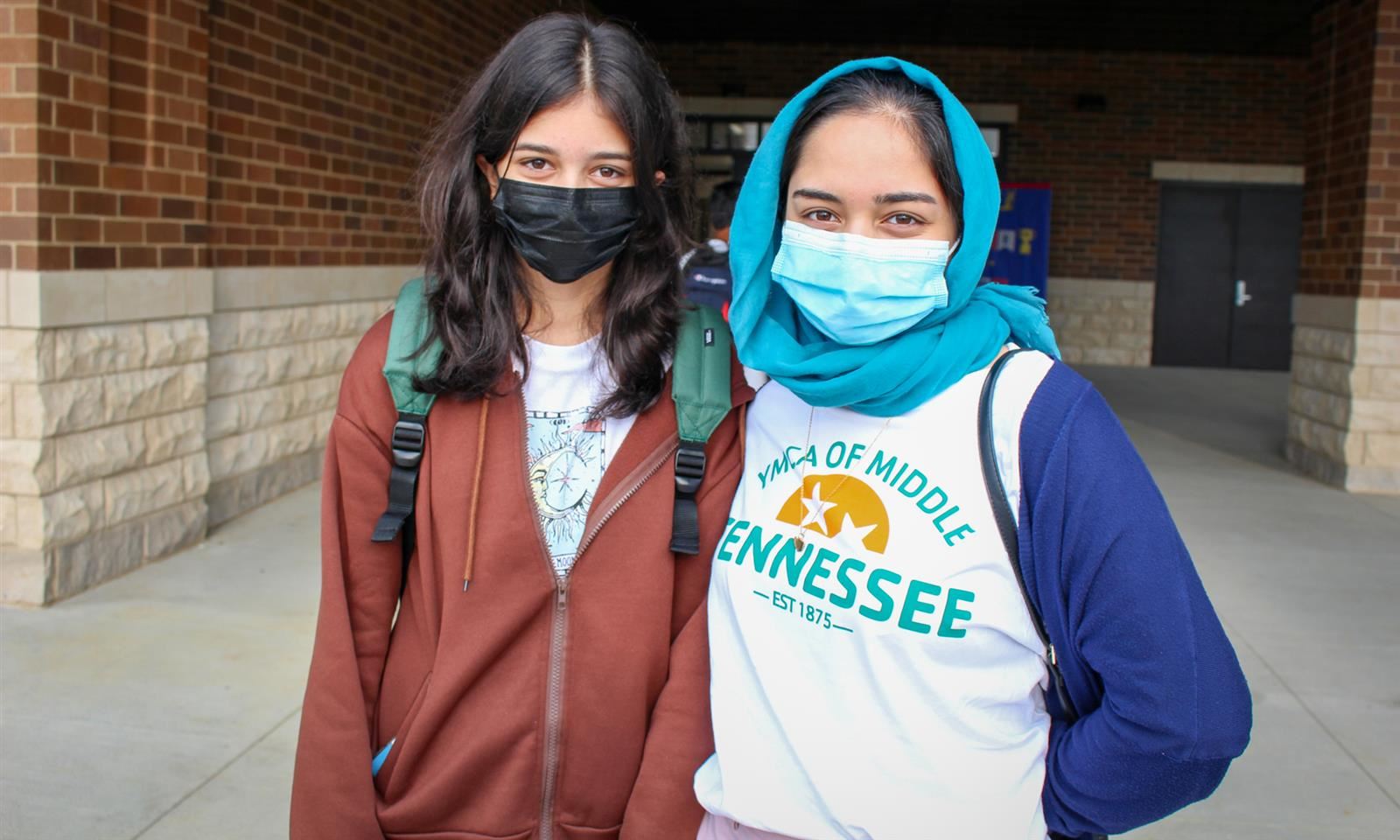 Two girls wear masks outside their school